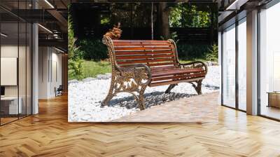 An empty park bench on a sunny summer day Wall mural