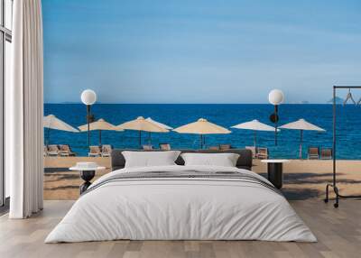 beach umbrellas with sun beds without people on a sandy beach against the background of the sea or ocean Wall mural