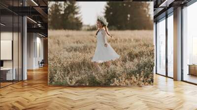 happy joyful young girl in a white dress and with a flower wreath on her head in the field in the summer Wall mural