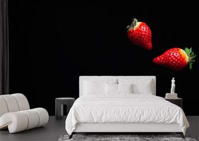 two ripe juicy red strawberries fly fall in the air on a dark background Wall mural