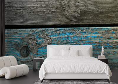 The textured surface of old wooden planks displays layers of weathering and a striking blue hue under bright sunlight. Wall mural