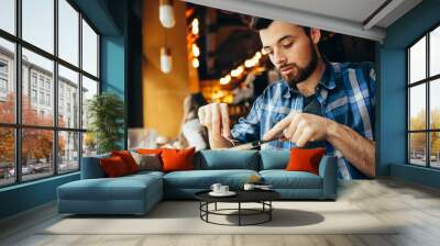 Handsome young man having lunch in elegant restaurant alone Wall mural