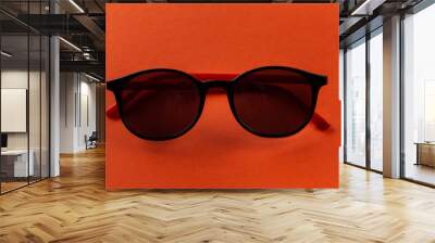 Stylish black sunglasses on an orange background folded. Fashion accessories. Wall mural