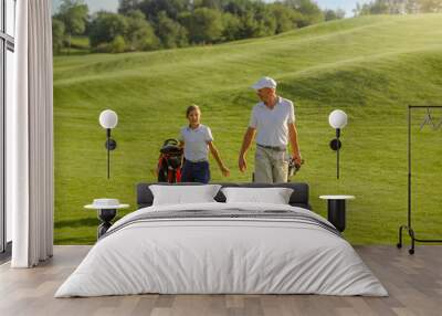 Boy and man golfers walking on golf course with carts Wall mural