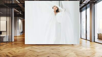 A graceful woman posing with a large wide-brimmed hat. Wall mural