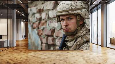 Focused soldier in combat uniform standing against a brick wall background Wall mural