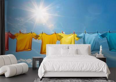 Freshly washed colorful t-shirts are drying on a clothesline in the sun Wall mural