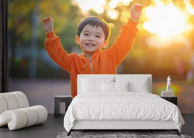 Happy child raising arms in the air at sunset Wall mural