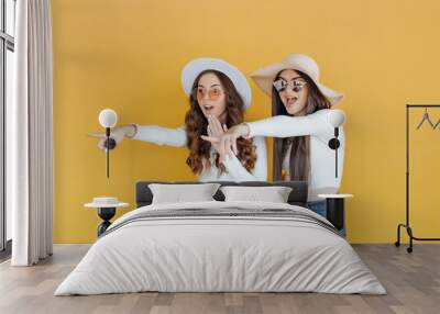 Picture of Two shocked girls pointing and looking away over yellow backgr Wall mural