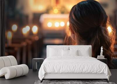 Woman praying in church with candles lit during mass Wall mural