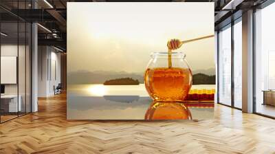 3D Honey jar with wooden honey stick dipping some pure sweet honey bee organic food shiny golden brown color on glossy table and some melt fluid blurred soft light color natural view background Wall mural