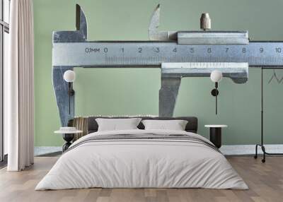 Calipers and stack of coins close-up against green wall. Wall mural