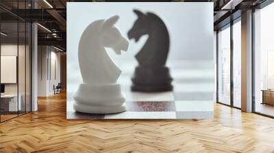 White chess horse close up on a black horse in a blur. The concept of confrontation. Chess is an strategy and intelligence board game. Wall mural