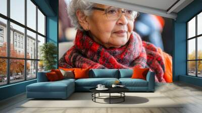 A woman with glasses and a red scarf is sitting in a chair Wall mural