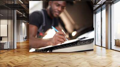 african auto mechanic making notes during work, focus on pen and notebook Wall mural