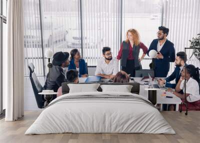 African corporate business coach explains basic principles of corporate strategy to diverse mixed-race employees at their first meeting at conference room. Wall mural