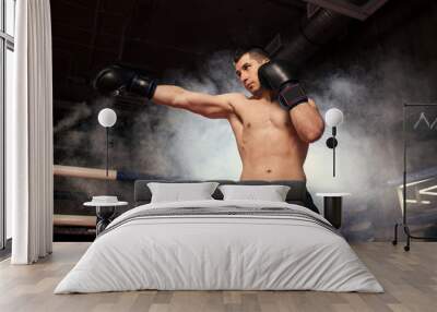 athlete boxer man with naked skin, wearing protective boxing gloves leaves agression in ring. Sporty lifestyle, box concept Wall mural