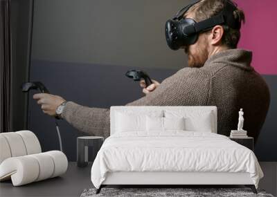 bearded man using the virtual reality headset and two controller Wall mural