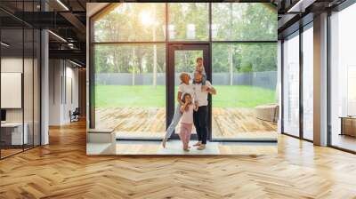 Beautiful and happy family together at home with panoramic window standing. Baby sit at daddy's head. Hug each other Wall mural