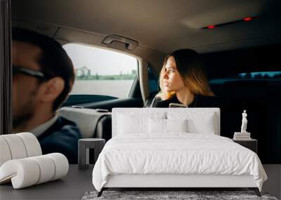 business woman using smart phone and smiling while sitting on back seat in car Wall mural