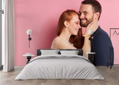 Caucasian couple of young two person stand hugging, posing at camera. Woman has red hair, man has beard Wall mural