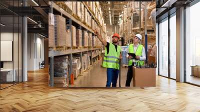 Caucasian warehouse managers walking through large warehouse distribution center discussing about increasing productivity. good teamwork, dressed in working clothes vest and hard hats Wall mural