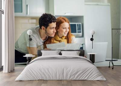 cheerful young couple calculating their bills at home Wall mural