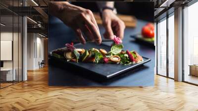 chef sprinkling spices on dish in commercial kitchen Wall mural