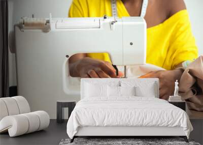 Close-up african seamstress hands working on sewing machine at home Wall mural