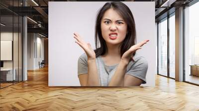 Close up isolated portrait of young annoyed angry Asian woman holding hands in furious and questioning gesture. Negative human emotions, face expressions. Wall mural