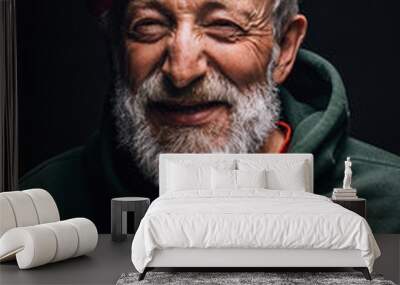 Close up portrait of happy 70-year-old optimist man with smiling wrinkled face, dressed in hipster orange hat and green hoodie, isolated over black background. Positive and cheerful at any age. Wall mural