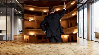 confident man in suit talking giving motivation training from speaker stage, handsome male of caucasian american european appearance raising hand, back view. people, success, performance Wall mural