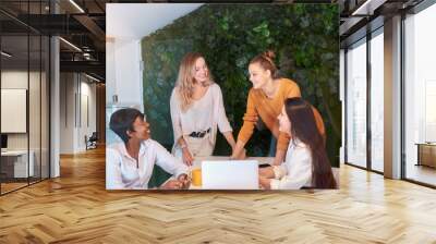 Confident young beautiful caucasian and african women hold meeting in modern green office, discussion of new business ideas and projects. business startup concept Wall mural