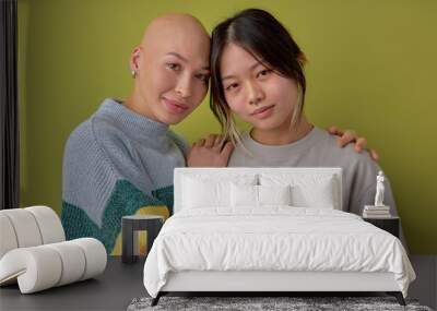 Diverse women posing at camera supporting each other, asian and another caucasian bald models, looking at camera smiling. Portrait of ladies in casual outfit having close relationships. alopecia Wall mural