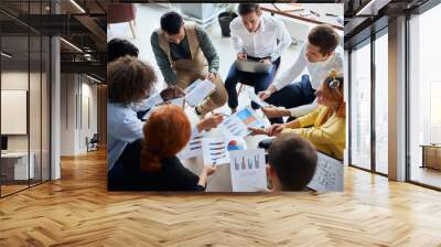 Diverse young people of business team gathered to discuss business startup in modern office, sit together in circle holding papers with diagrams. active discussing Wall mural