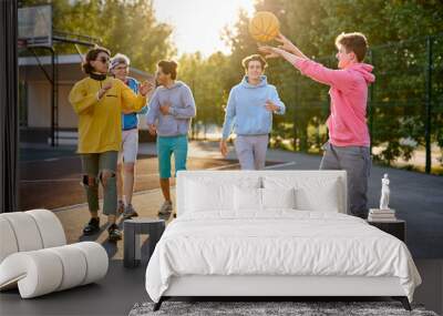 energetic, healthy teens have fun, talk before playing basketball, group of happy teenage boys in colourful casual wear, playing basketball outdoors in the city, go at playground Wall mural