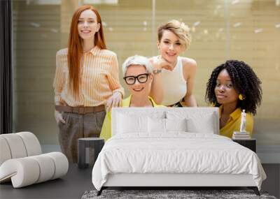 four beautiful models in in trendy clothes looking at the camera. close up photo. blond sexy woman an her team help you to change your image Wall mural