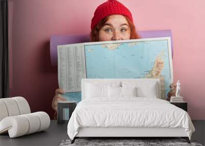 funny tourist hiding behind the map, close up portrait, isolated pink background, studio shot, lifestyle Wall mural