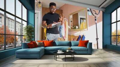 handsome black fashion blogger man talk about advantages sneakers, use devices for broadcasting, camera and light. at home Wall mural