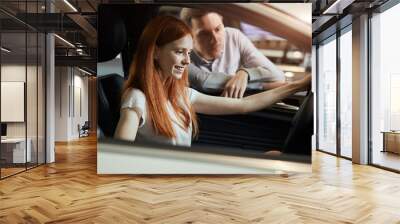 Happy caucasian female client seats in new car on driver s seat and male sales rep telling about car features and high points. Wall mural