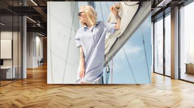 Happy woman on sailing ship stretching hand to her male parner, beautiful young carefree woman in sunglasses stands against white sails. Love smile, concept summer ocean holiday travel. Wall mural