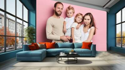 Happy young family with adoravle little daughters posing on pink background, close up portrait, solated pink background studio shot. relationship Wall mural