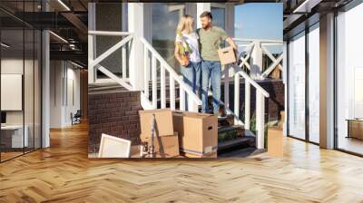 Husband and wife standing in front of new buying home with boxes. bought first home Wall mural