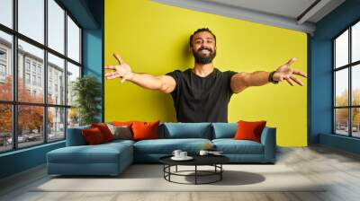 let's hug you. young positive man with spread arms look at camera, isolated on green background Wall mural