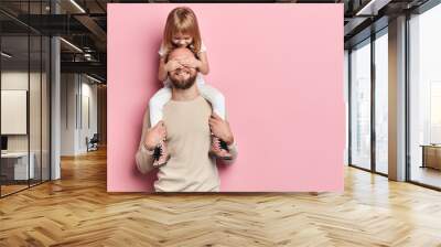 little daughter covering her dad's eyes with a palm. girl having fun with dad. happiness, close up portrait, isolated pink background, copy space Wall mural