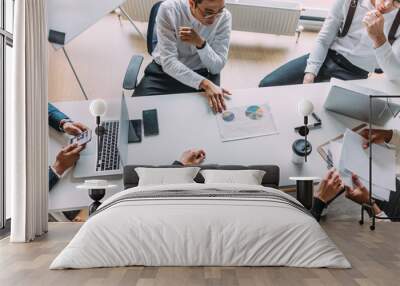 Multiracial group of young people in formal wear making out business plan for future start-up project sitting at the desk. Corporate Work Concept . Top view. Wall mural