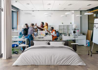 open plan room with mixed race energetic students giving high five to each other. copy-space Wall mural