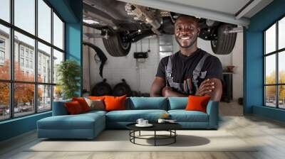 portrait of positive afro american auto mechanic in uniform posing after work, he is keen on repairing cars, automobiles. Wall mural