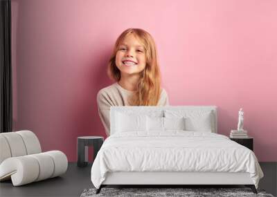 Portrait of positive cheerful girl cutely smiling at camera, girl with long golden hair in white blouse. Pink background Wall mural