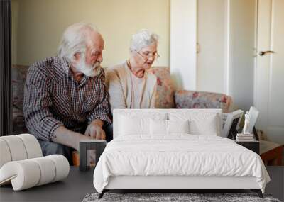 Senior european couple of pensioners sitting in cozy living room looking at photos from their wedding day and first child birth and recollecting happy moments of life. Happy family, old age concept Wall mural